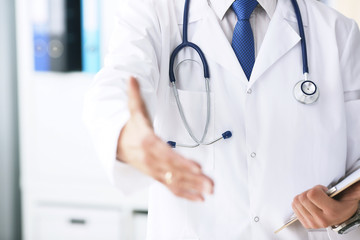 Male medicine doctor hold pad and give arm to shake in office closeup. Friend welcome introduction or thanks gesture. Work examine patient congratulation help exam teamwork deal concept.