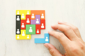 business concept image of tangram puzzle blocks with people icons over wooden table ,human...