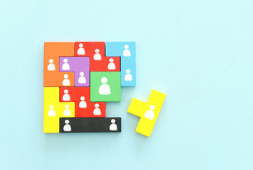 business concept image of tangram puzzle blocks with people icons over wooden table ,human...