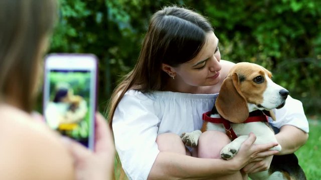 Girl photography woman on mobile phone who hugs and kisses a cute beagle dog