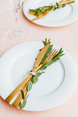 Festive table setting for celebrate event or family dinner with two plates and golden cutlery on a pink tablecloth.