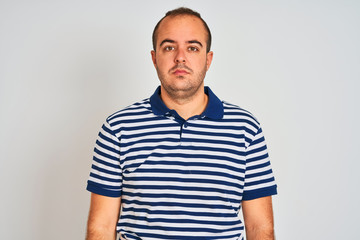 Fototapeta premium Young man wearing casual striped polo standing over isolated white background Relaxed with serious expression on face. Simple and natural looking at the camera.