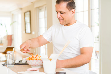 Middle age man eating asian food at home