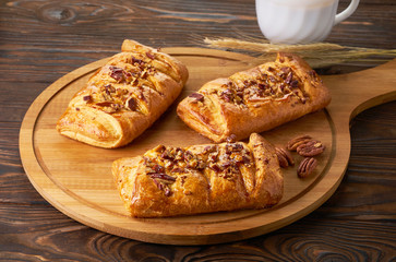 Danish pastry maple pecans with nuts and maple syrup on wooden table