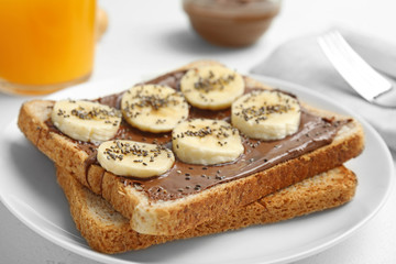 Slice of bread with chocolate paste and banana on table, closeup