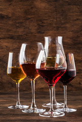 Wine set. Red, white and rose wine in assortment in wineglasses. Wine tasting, vintage wooden background, selective focus, copy space