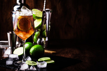 Alcoholic cocktail Long Island with vodka, gin, tequila silver, white rum, liqueur, sugar syrup, lemon juice, cola and ice cubes, vintage bar wooden counter background, selective focus