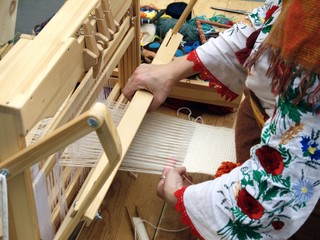 Hands of the weaver who weaves fabric on a retro loom