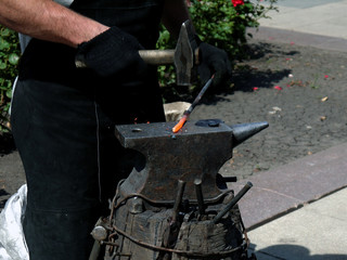 The photo of the hands of a blacksmith forging iron