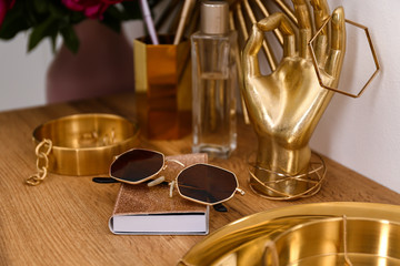 Composition with gold accessories on dressing table near white wall
