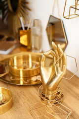 Composition with gold accessories and jewelry on dressing table near white wall