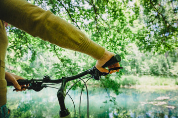Woman holding bicycle handle in front of water obstacle in green forest