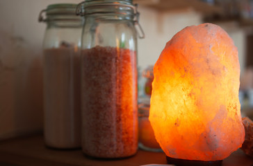 Saltlamp and jars with coarse himalaya salt close up