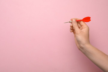 Woman holding red dart arrow on pink background, closeup with space for text