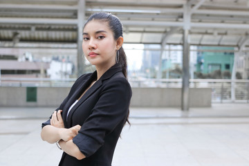 Confident young Asian business woman crossing one's arms at outside office.