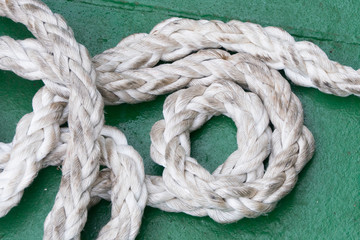 Fototapeta na wymiar A section of ships rope lies coiled on a green floor - Image_