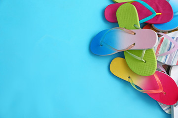 Obraz na płótnie Canvas Heap of different flip flops and space for text on blue background, top view. Summer beach accessories