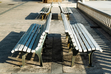 rays of sunshine on group of white benches on sidewalk in the morning