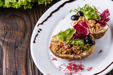 Twice baked potato stuffed with tune on white plate