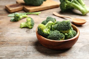 Bowl of fresh broccoli on wooden table. Space for text