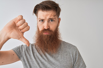 Young redhead irish man wearing t-shirt standing over isolated grey background with angry face,...