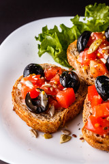 Italian bruschetta with tomato, black olives, lettuce and mustard