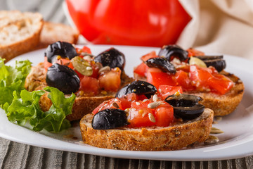 Italian bruschetta with tomato, black olives, lettuce and mustard