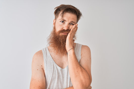 Young redhead irish man wearing t-shirt standing over isolated grey background thinking looking tired and bored with depression problems with crossed arms.