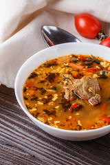 Georgian soup. Kharcho with rice, tomato, beef, garlic and herbs in bowl on wooden table