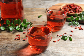 Healthy goji juice in glasses on wooden table