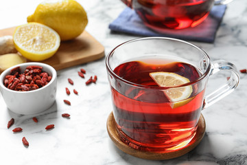 Healthy goji tea with lemon in glass cup on marble table