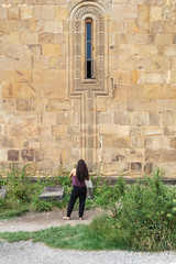 Fototapeta na wymiar Girl at the wall of the old Church