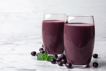 Tasty acai drink in glasses and berries on marble table