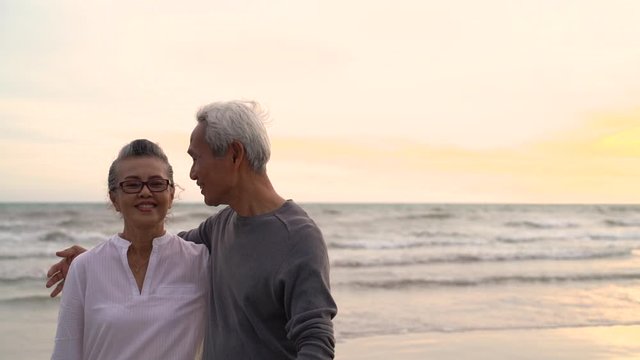 Asian couple senior elder retire resting hugging at sunset beach honeymoon family together happiness people lifestyle, Slow motion footage