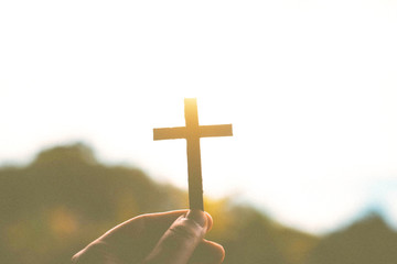 Silhouette of human hands holding a cross holy