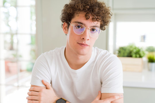Young handsome man wearing glasses Relaxed with serious expression on face. Simple and natural with crossed arms