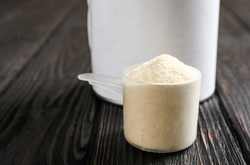 Scoop of protein powder on black wooden table