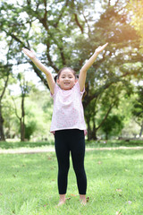 Happy little girl raised her hand with green park background