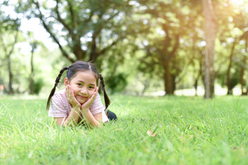 Naklejka na ściany i meble Little cute girl smiling & laying on the grass