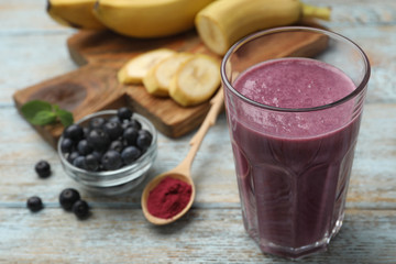 Fresh acai drink with powder and berries on wooden table