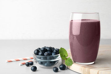 Fresh acai drink with berries on grey table against light background. Space for text