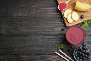 Fresh acai drink with berries and banana on dark wooden background, flat lay. Space for text