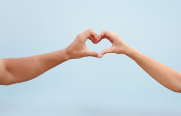 Happy couple making heart with their hands against blurred landscape