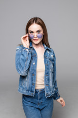 Attractive smiling happy woman making selfie photo isolated on white studio background dressed jeans and denim shirt wearing yellow sunglasses hipster style outfit