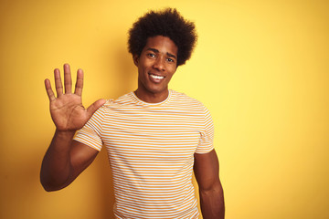 American man with afro hair wearing striped t-shirt standing over isolated yellow background...