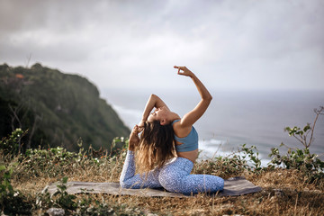 Girl practice yoga near ocean.