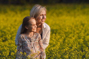 The concept of parenting. Beautiful mother and daughter on a yellow rape field