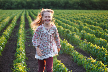 Lifestyle. A carefree charming girl runs in a field with flowers at the summer sunset