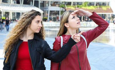 Two female friends walking ina modern city and talking