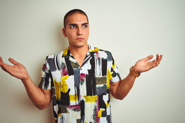 Young handsome man wearing summer shirt over white isolated background clueless and confused...